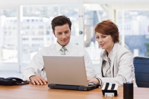 Portrait of a happy young business people working on laptop discussing